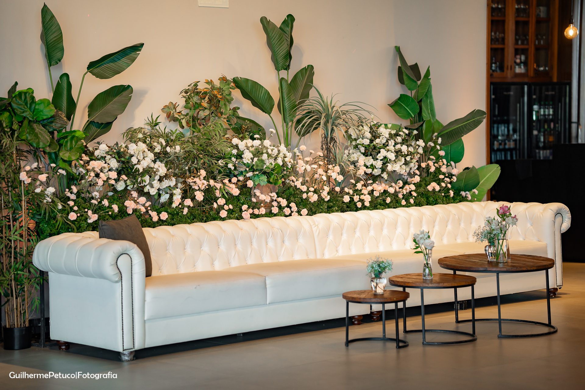 Lounge com sofá Chesterfield branco e parede florida